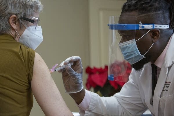 A man uses a needle to administer a vaccine. 