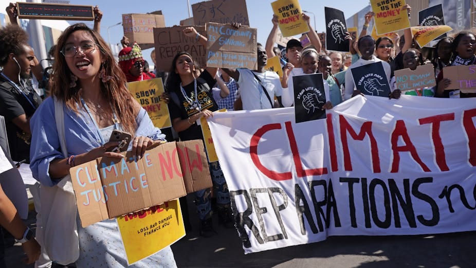 A group of people holding placards outdoors. A group of people holding placards outdoors.