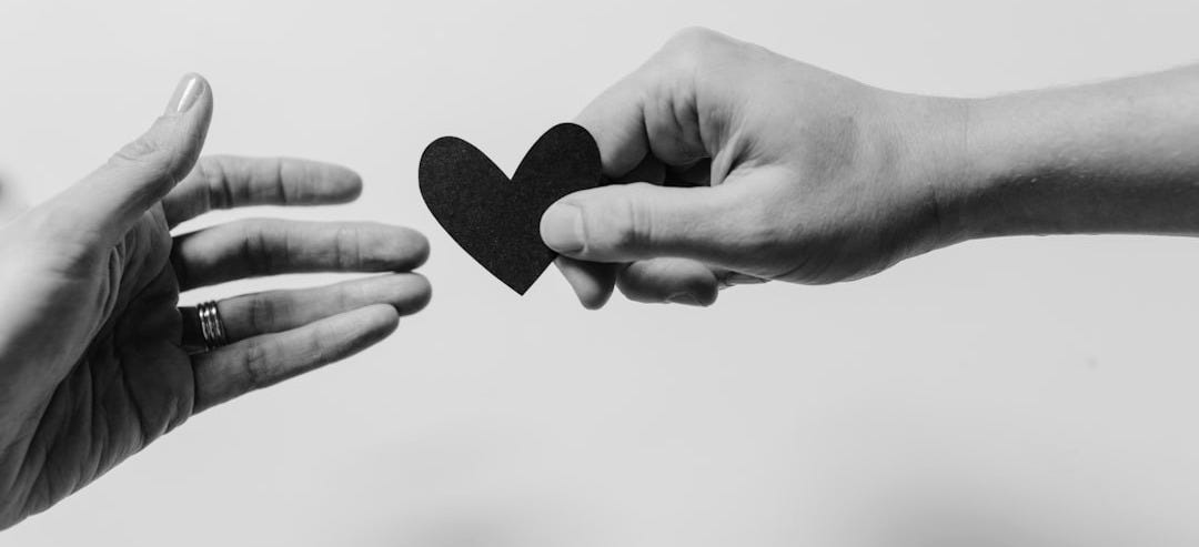 person reaching black heart cutout paper