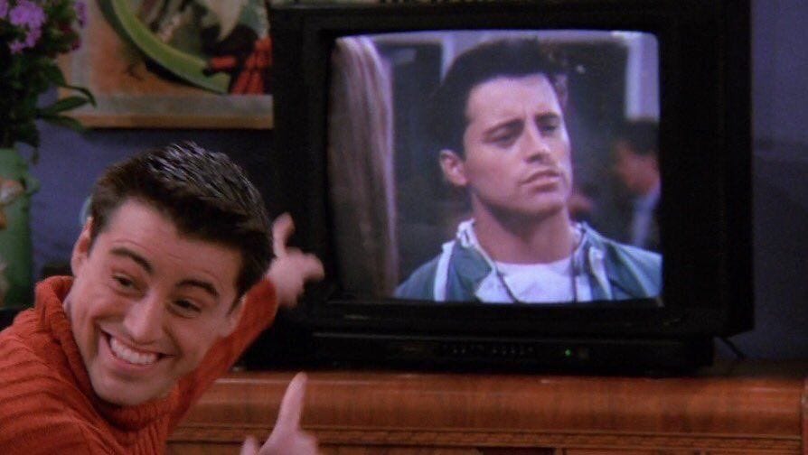 Meme of Joey Tribbiani from Friends smiling and pointing excitedly at a TV screen that shows a serious version of himself, with the caption: "Me when our content shows up on Google and LLMs."