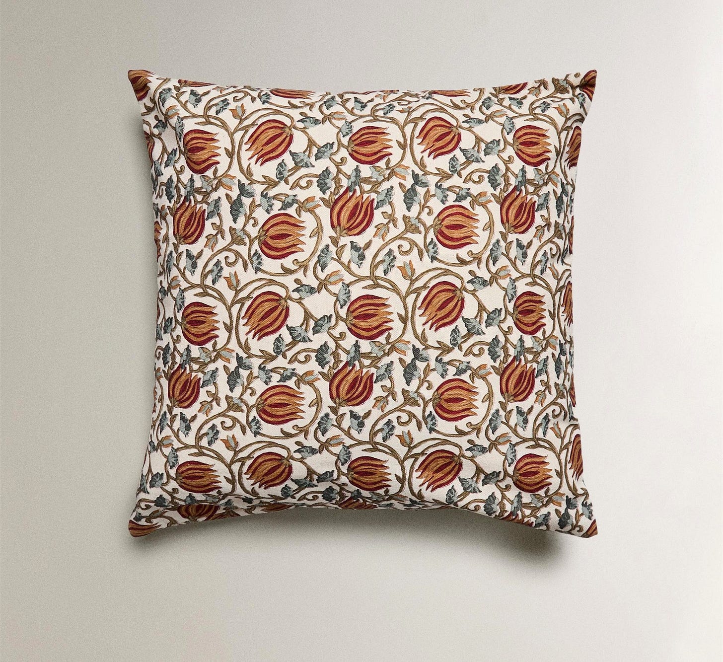 Front view of a cushion with a floral print in brown and green tones on a white background.