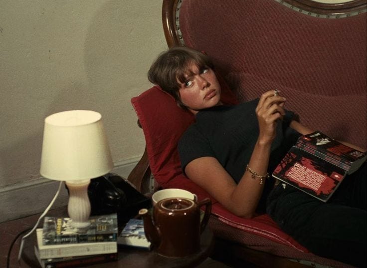 This may contain: a woman sitting in a chair with a book on her lap next to a lamp