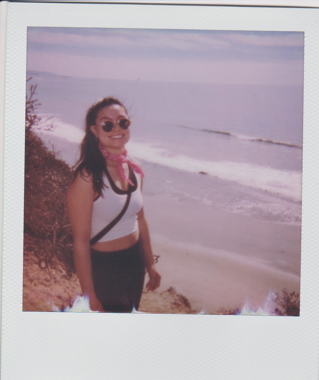 Liza smiling on a cliff above the shore.