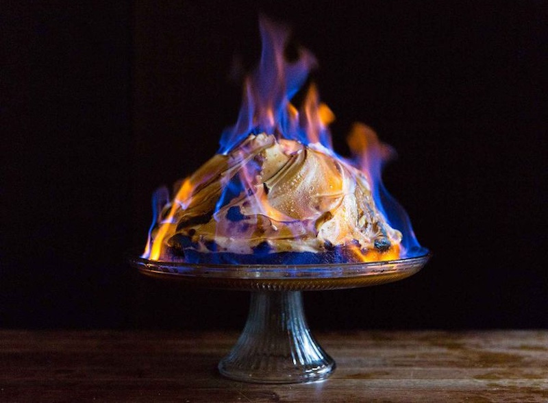 Photo of baked Alaska desert burning on a raised silver platter.