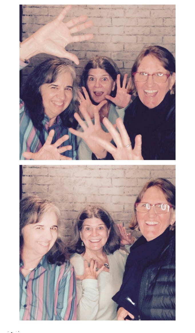 Three women in a Photo Booth. Picture with jazz hands and another looking happy.
