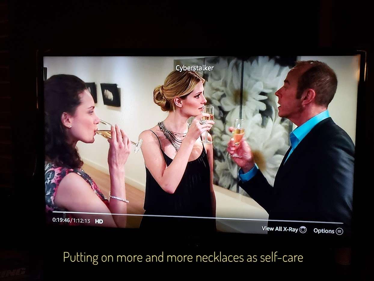 Aiden, Jill, and Winton dressed up and drinking champagne at the gallery, Aiden is wearing at least a dozen necklaces. Captioned "Putting on more and more necklaces as self-care"
