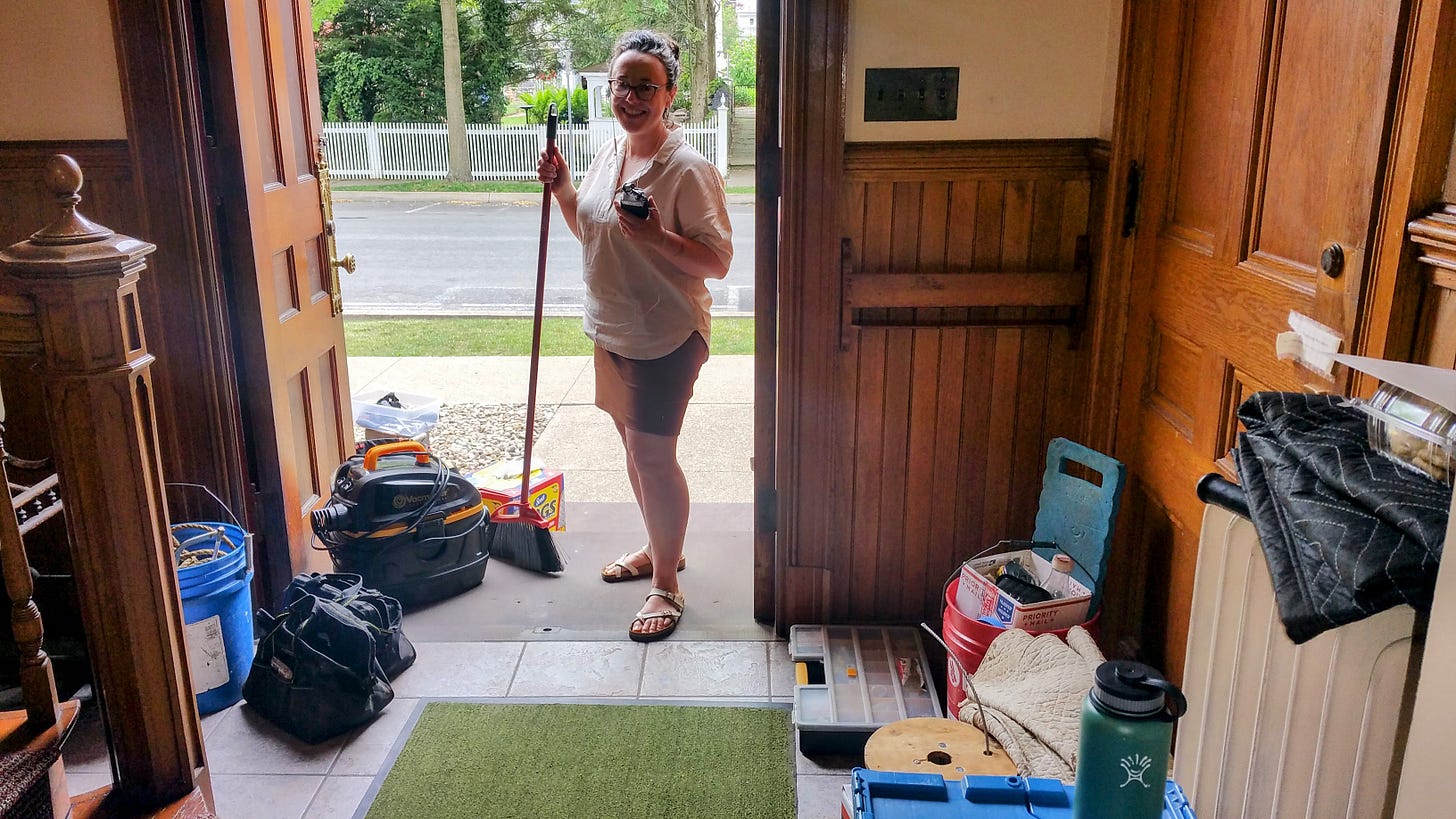 Woman holding a broom and a recorder inside an open door.