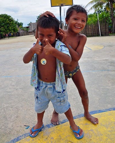 Two little boys, one with jean shorts and the other in underpants, having fun for the camera on a basketball court. 
