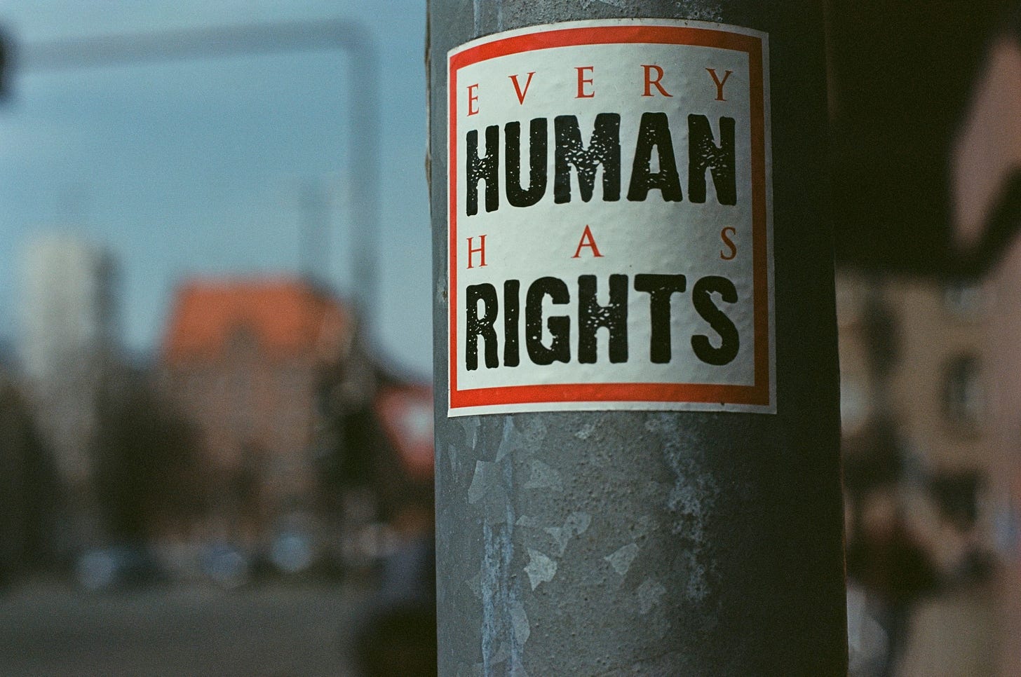 A sticker reading “Every Human Has Rights” posted on a street pole, reflecting public calls for universal human rights and accountability.