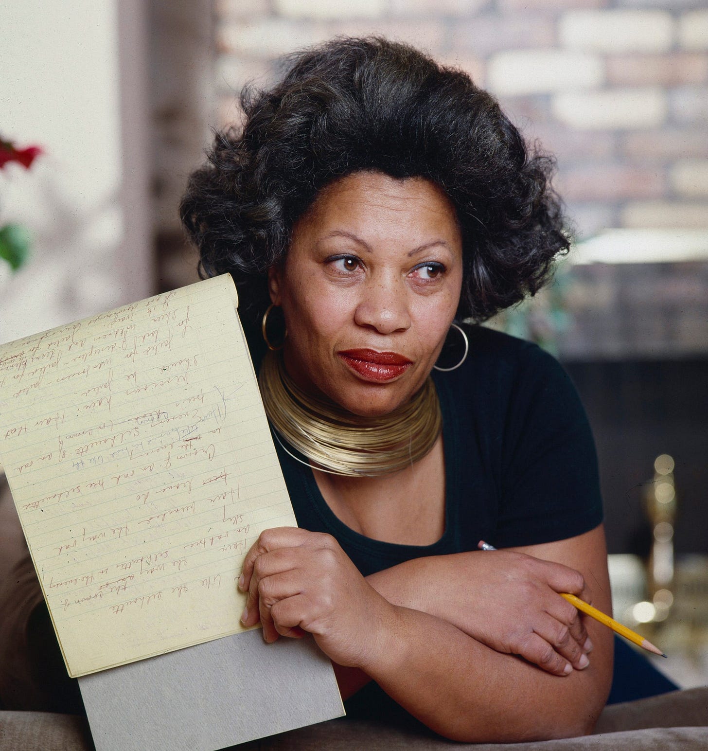 Toni Morrison holding a notepad and pencil.