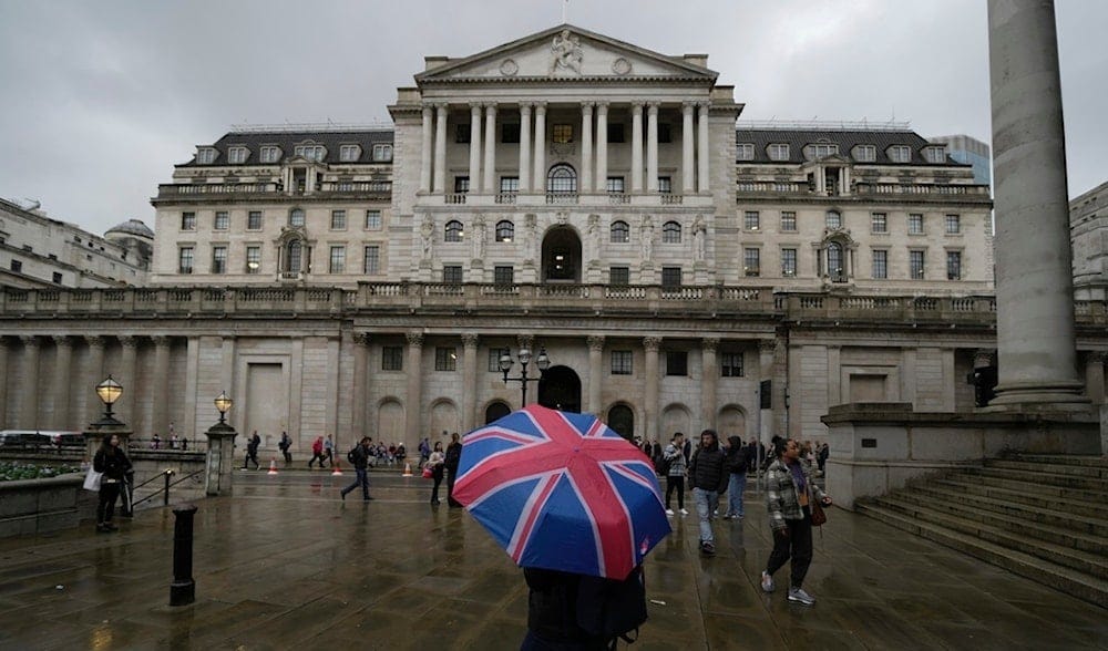 A woman with an umbrella stands in front of the Bank of England, at the financial district in London, , Nov. 3, 2022. (AP)