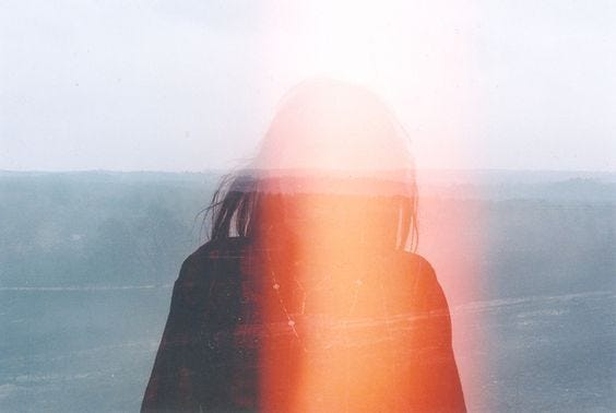 This may contain: a woman standing in front of a window with her back to the camera looking out