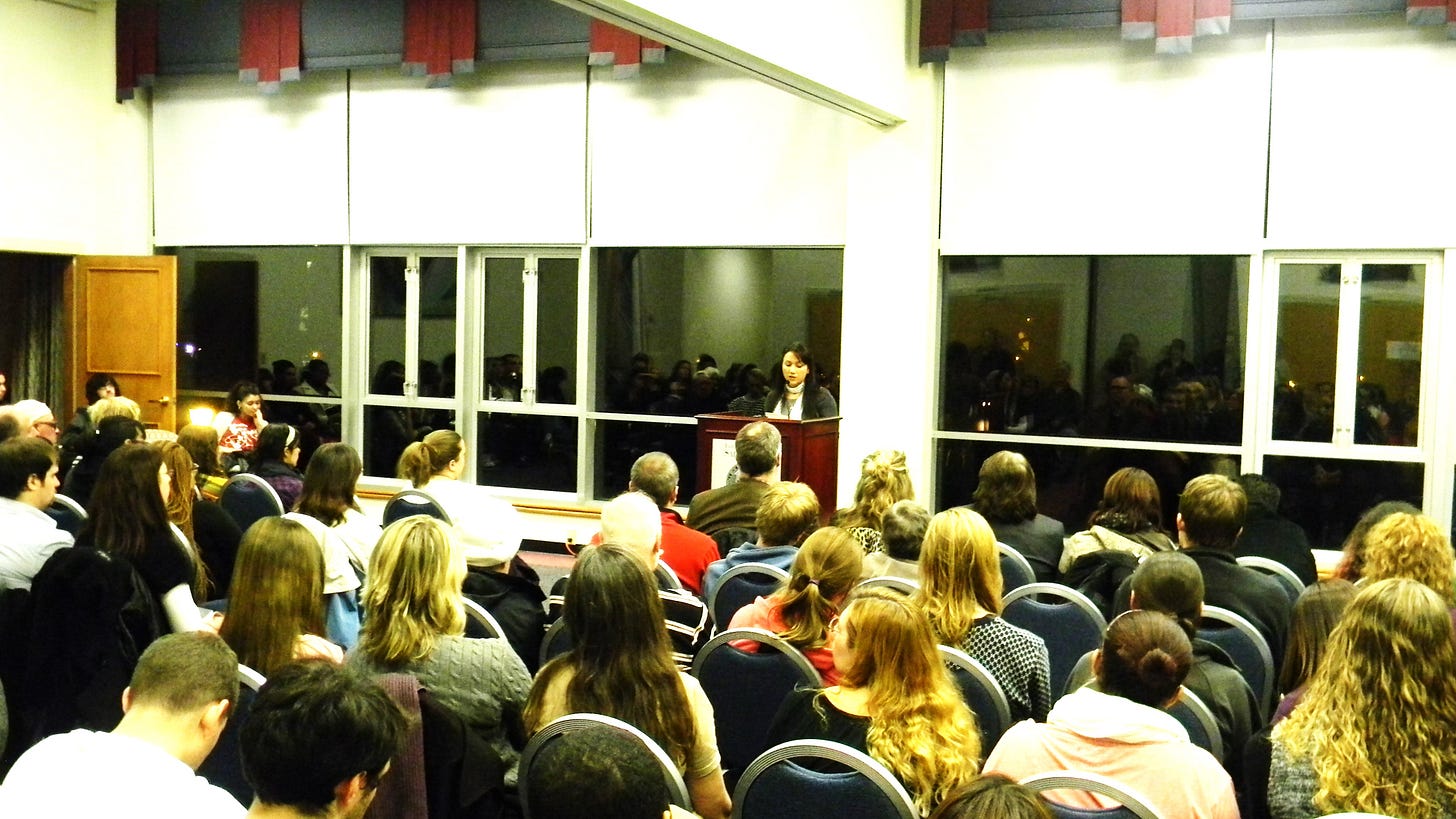 Photo of Melissa Febos in front of an audience of 80 people in a college student center.