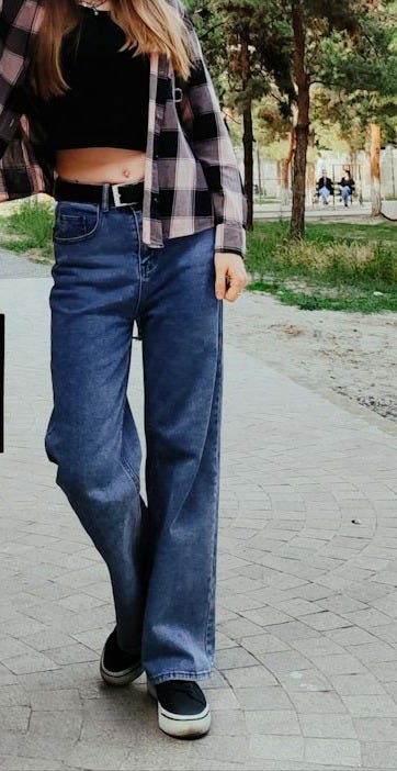 a woman standing next to a brick wall