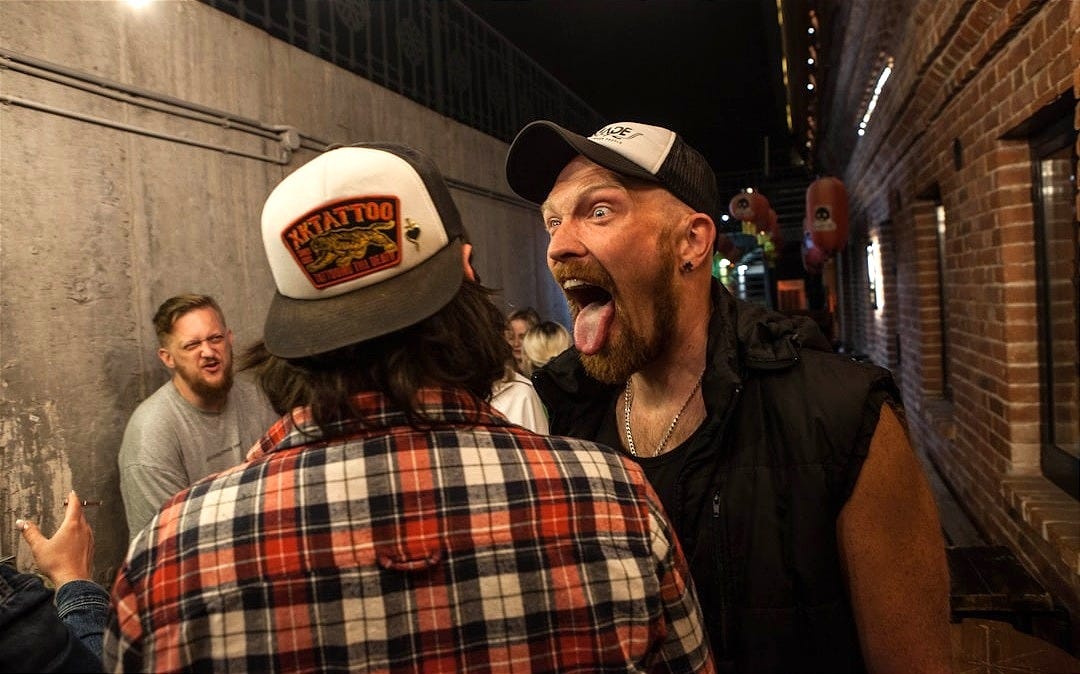 a man sticking his tongue out in a crowded alleyway
