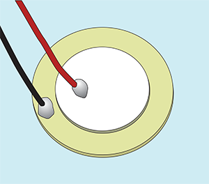 A round golden disk with a white disk sitting on top of it. One wire is soldered to each disk.