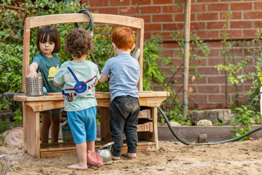 image of children playing at an outdoor mud kitchen.