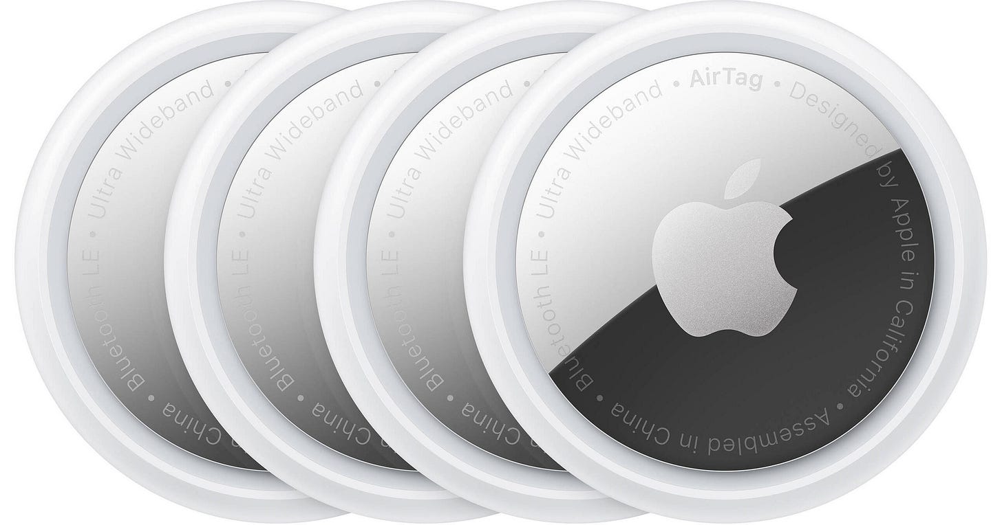 4 Apple AirTags which look like white buttons with silver centers with an Apple logo 4 Apple AirTags which look like white buttons with silver centers with an Apple logo