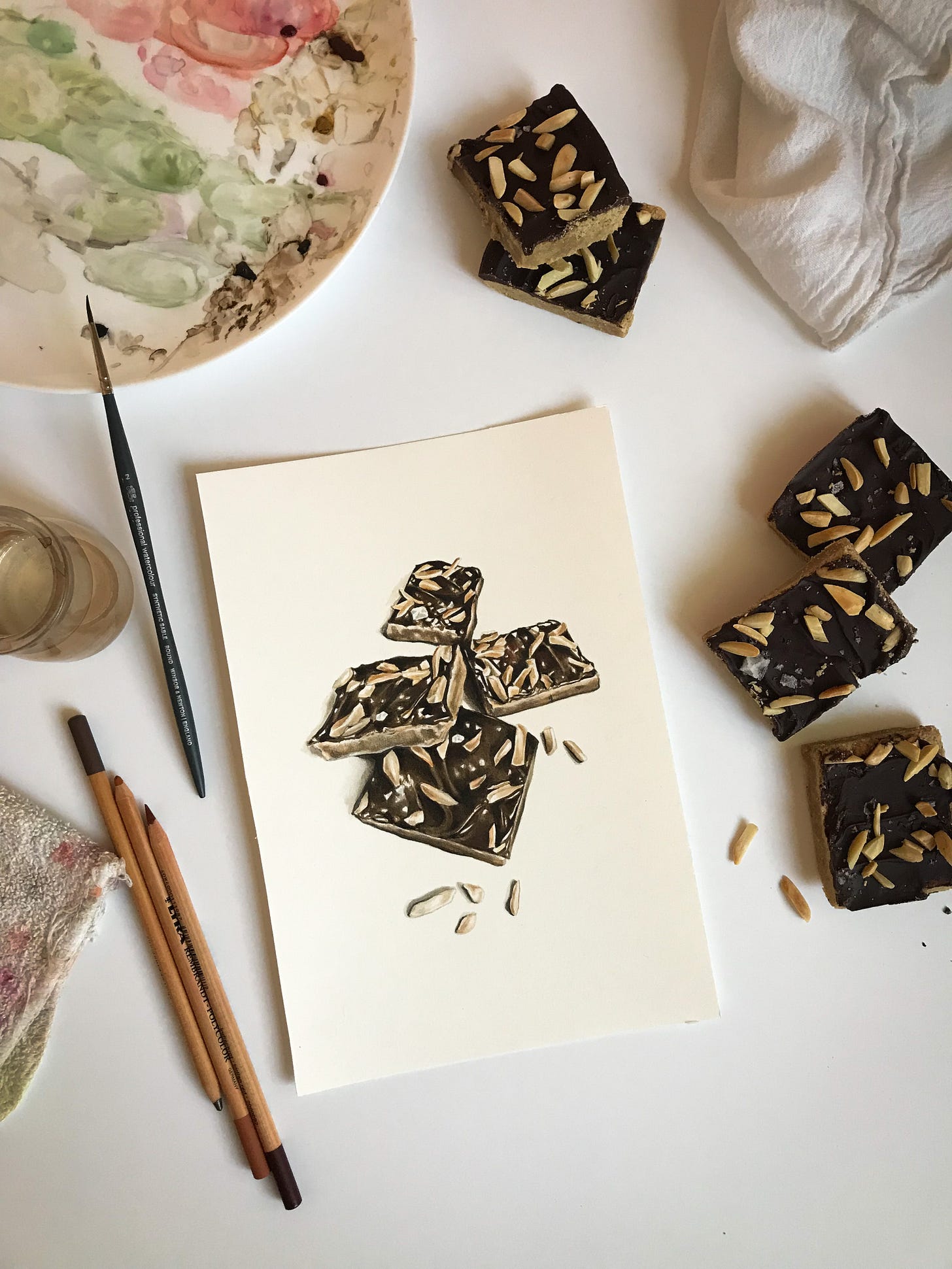 Toffee slice painting on work surface with painting materials and actual toffee slices next to the finished piece