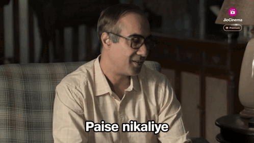 a man sitting in a chair with the words " paise nikalye " written on his chest