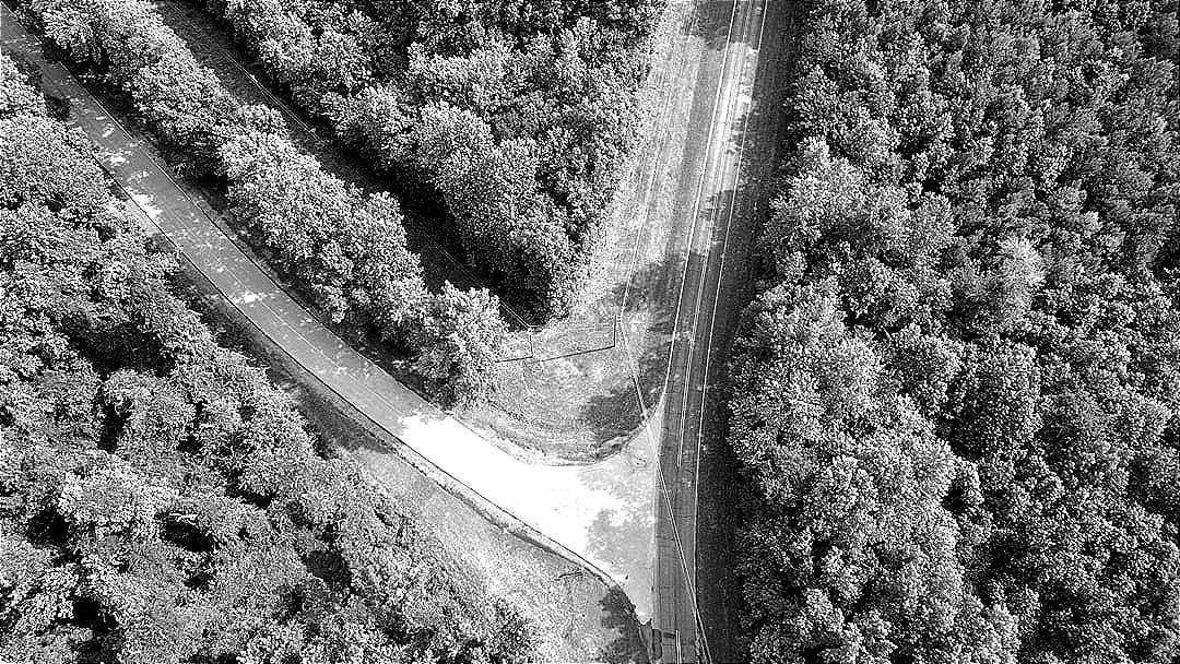An aerial view of a road in the middle of a forest An aerial view of a road in the middle of a forest