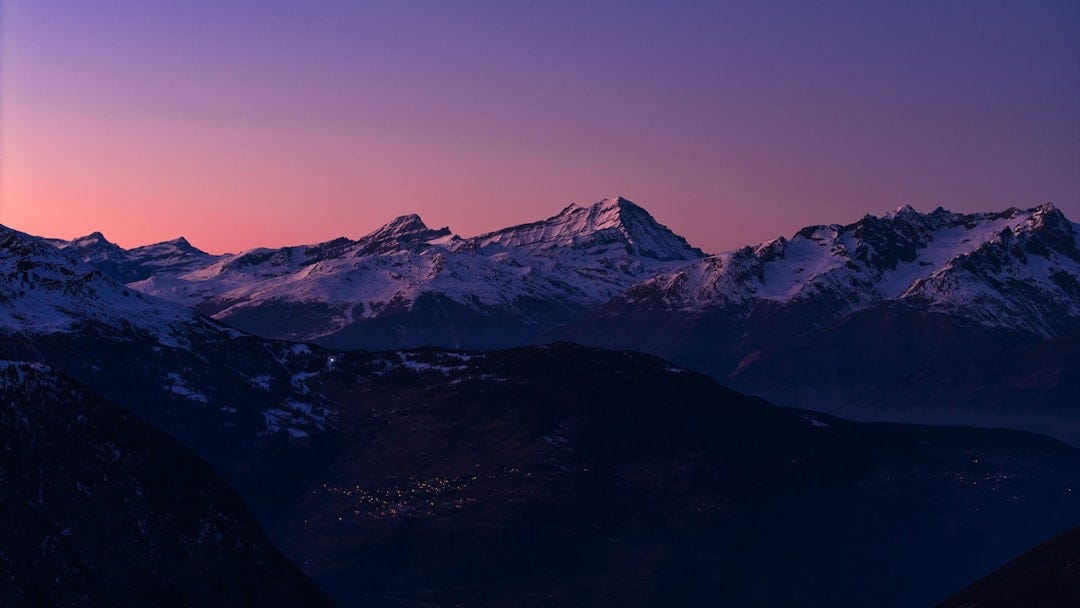 Snow-capped mountains under a purple and pink sky