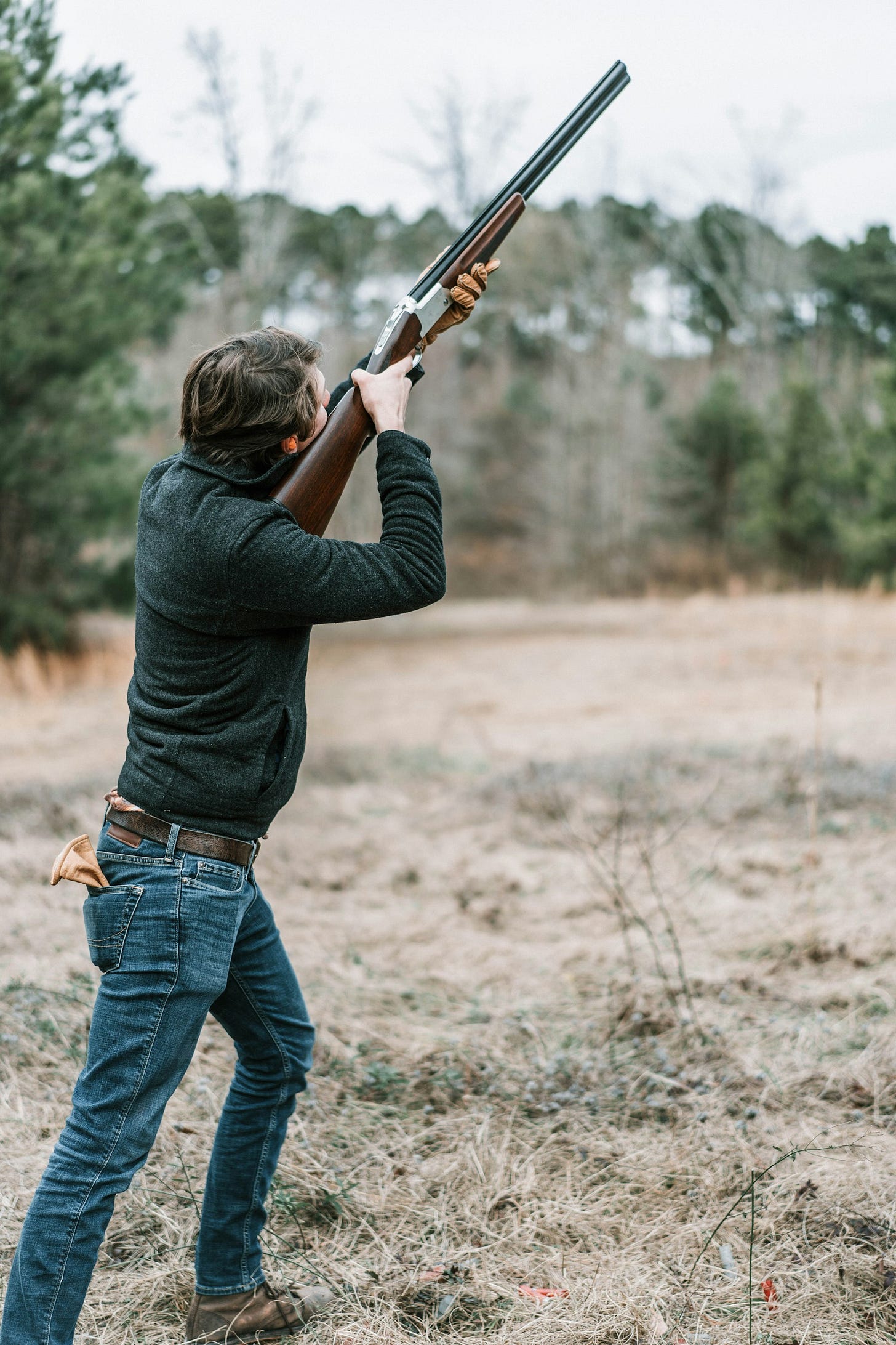 man in black long sleeve shirt and blue denim jeans holding brown rifle man in black long sleeve shirt and blue denim jeans holding brown rifle