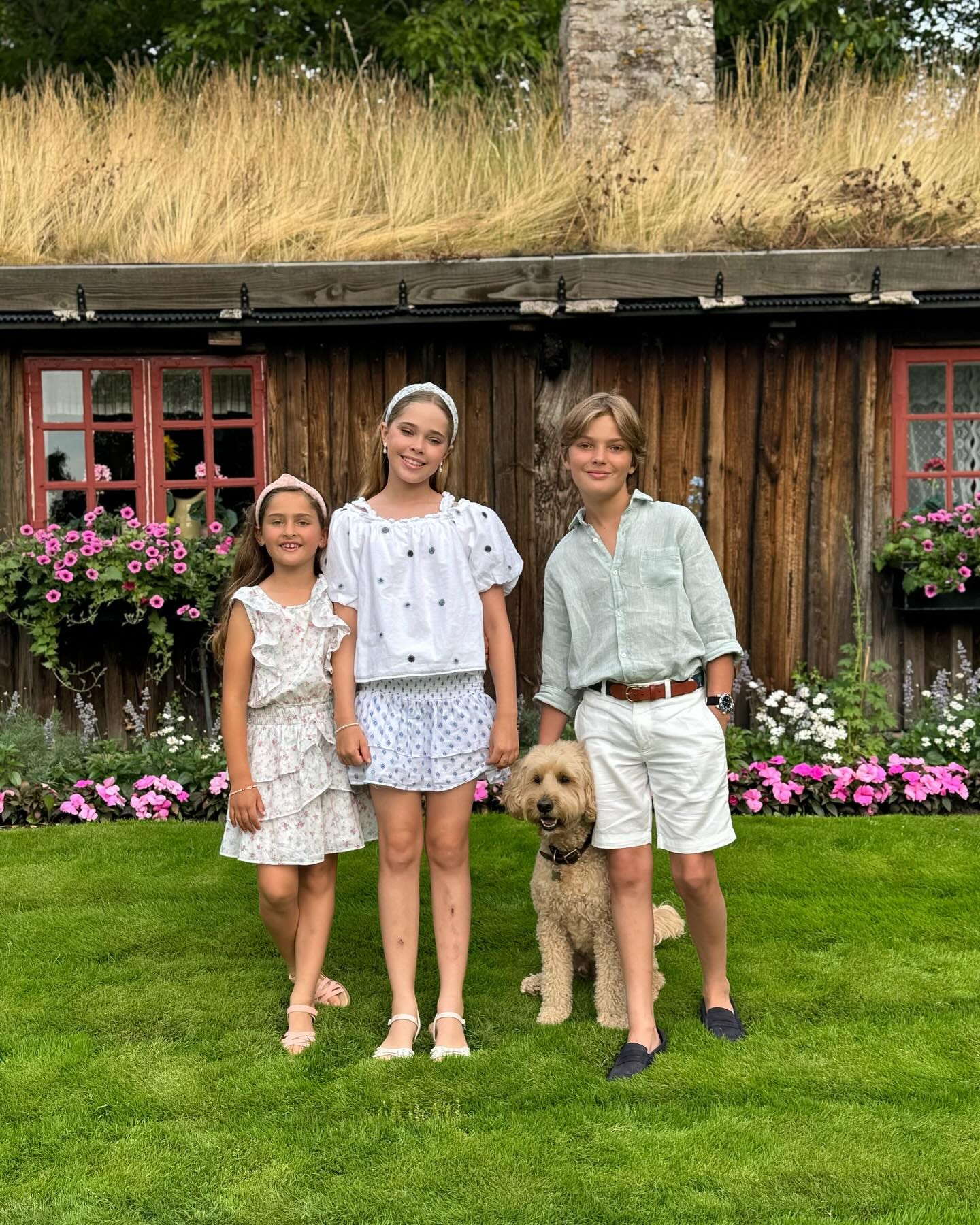 Princess Madeleine's three children standing in front of summer house with dog