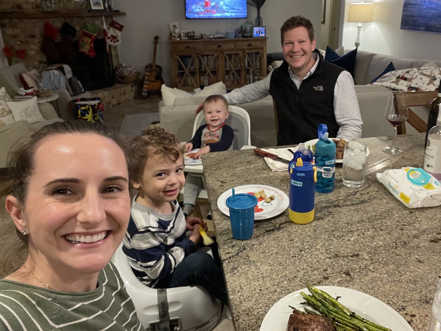 A Family sitting around a kitchen island eating dinner and smiling A Family sitting around a kitchen island eating dinner and smiling