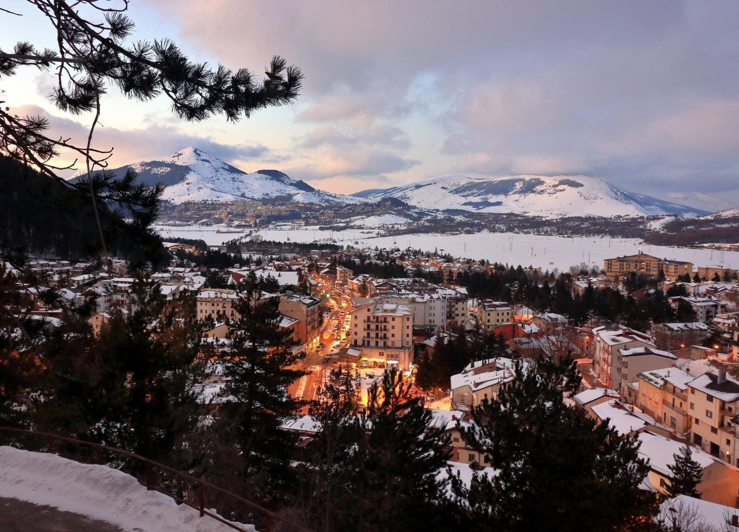 Evening view of Roccaraso, Italy with snow-covered mountains and a busy, lit street showing concentrated visitor activity in a small town Evening view of Roccaraso, Italy with snow-covered mountains and a busy, lit street showing concentrated visitor activity in a small town