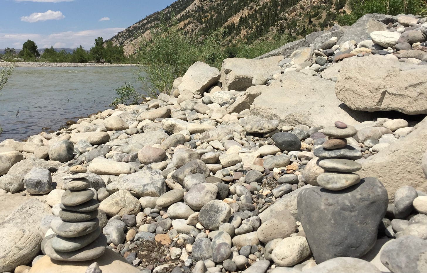 On the left a river and to the right river rocks with two cairns.