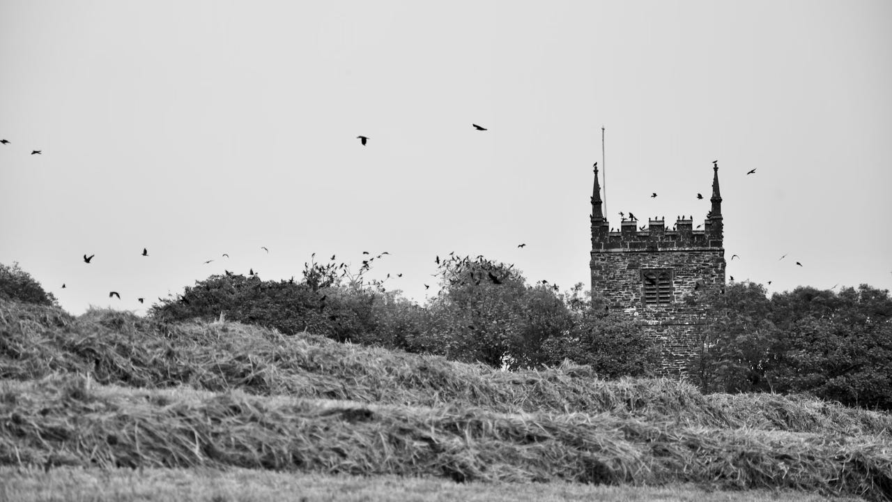 black and white photo of an English church tower rising above the landscape
