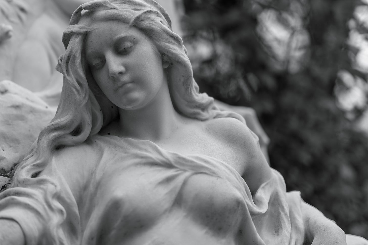 Black and white photo of a statue of a woman looking down with a sad expression on her face. Black and white photo of a statue of a woman looking down with a sad expression on her face.