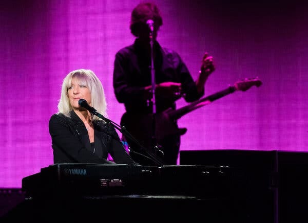 Christine McVie, seated at an electric keyboard and leaning into a vocal microphone (but not singing). Christine McVie, seated at an electric keyboard and leaning into a vocal microphone (but not singing).