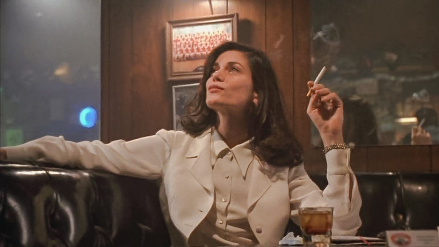 Linda Fiorentino in The Last Seduction (1994), lounging in a booth with a cigarette in hand and a cocktail on the table, dressed in a crisp white suit against a wood-paneled bar backdrop. Linda Fiorentino in The Last Seduction (1994), lounging in a booth with a cigarette in hand and a cocktail on the table, dressed in a crisp white suit against a wood-paneled bar backdrop.