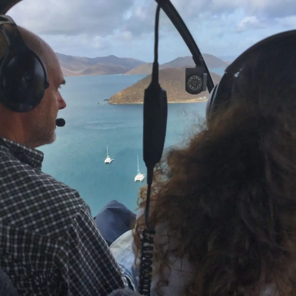 Ian sitting next to the helicopter pilot in flight