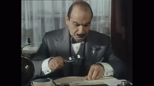 a man in a tuxedo is looking through a magnifying glass at a piece of paper . a man in a tuxedo is looking through a magnifying glass at a piece of paper .