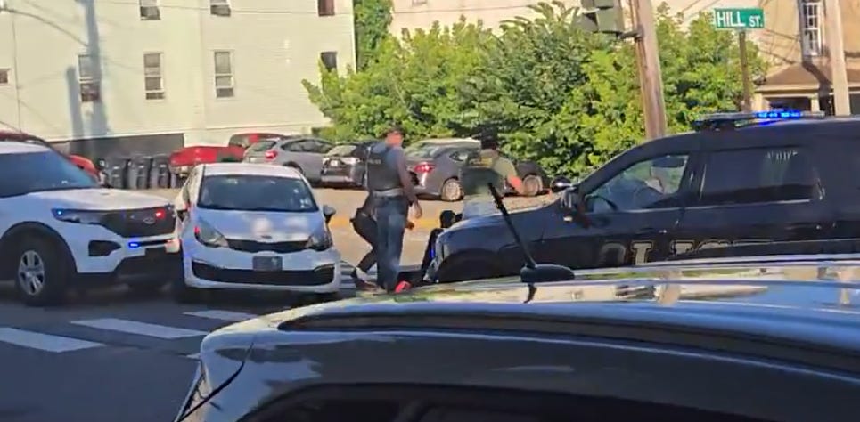 This image shows the car stopped by the unmarked ICE SUV that rammed it. The marked Biddeford Police unit responded to the scene after the shooting occurred. (frame grab from video clip “released by Portland Press Herald” posted by @factpostnews to x.com) This image shows the car stopped by the unmarked ICE SUV that rammed it. The marked Biddeford Police unit responded to the scene after the shooting occurred. (frame grab from video clip “released by Portland Press Herald” posted by @factpostnews to x.com)