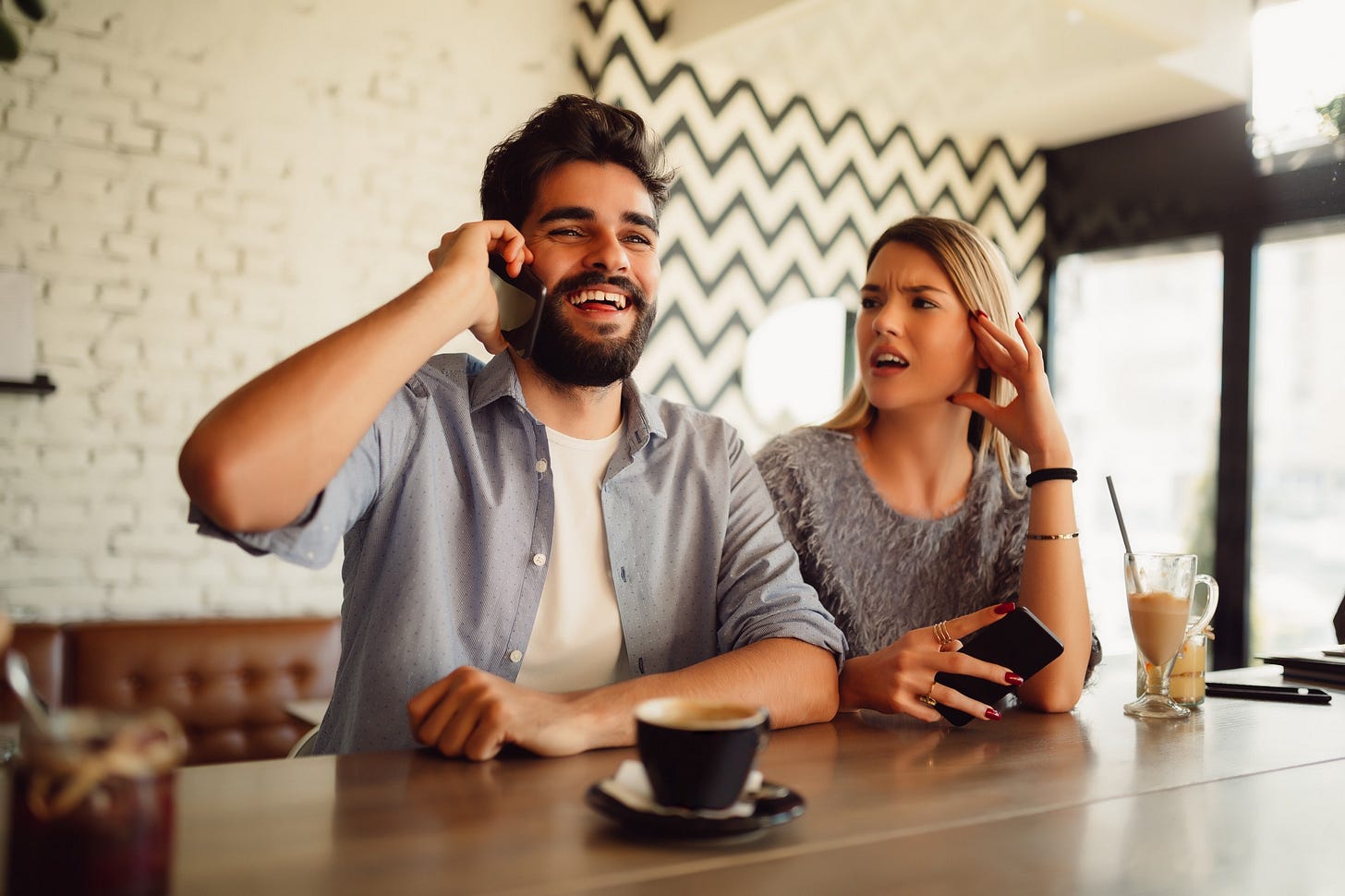 A woman is ignored by her crush while he laughs on the phone. A woman is ignored by her crush while he laughs on the phone.