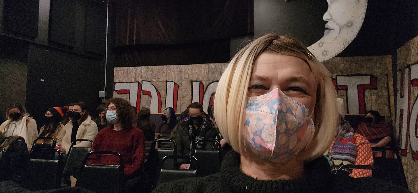 A photograph of Davi Gray, wearing a mask, seated in the event space at Moon Palace Books.