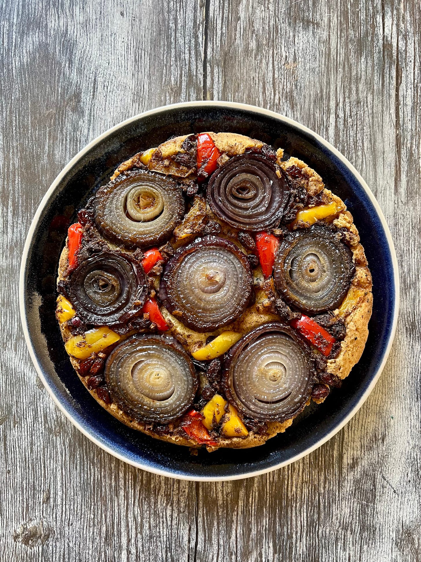 Rounds of sliced onion, peppers and raisins on top of a savoury scone base