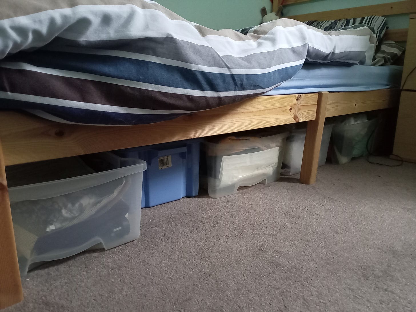 bed with plastic containers containing craft supplies underneath