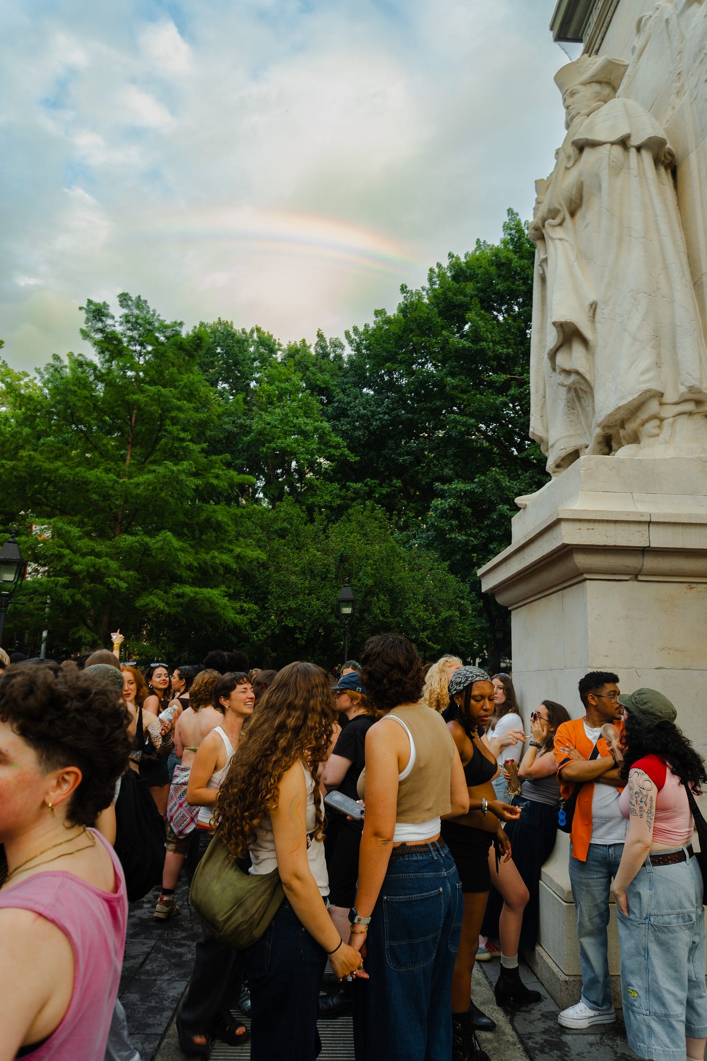 A couple holds hands while looking up at a rare triple rainbow that appeared towards the end of the dyke march