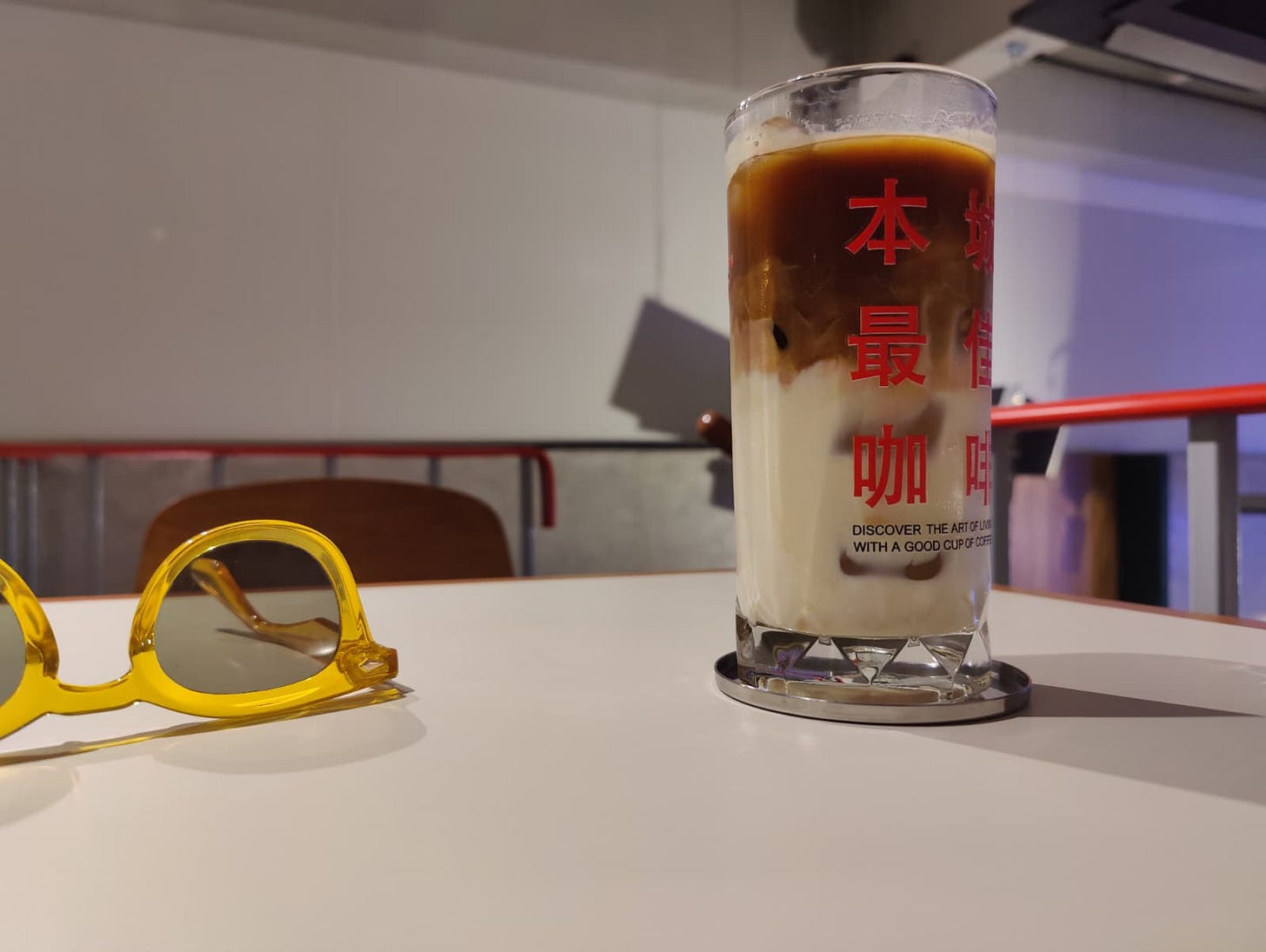 an iced oat latte in a highball glass with yellow sunglasses