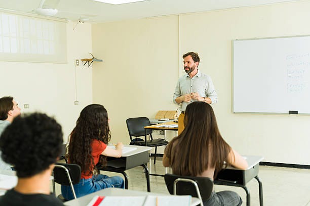 Male high school teacher giving lesson to students in classroom