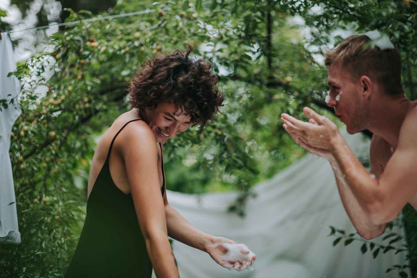 A couple playfully fights with one another outside in a green garden. A couple playfully fights with one another outside in a green garden.