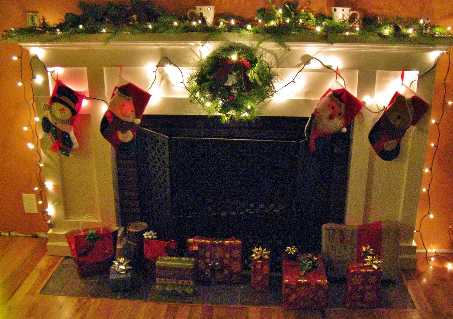 photo showing a more recent christmas time decorations - a fireplace with a few small presents and a wreath and lights