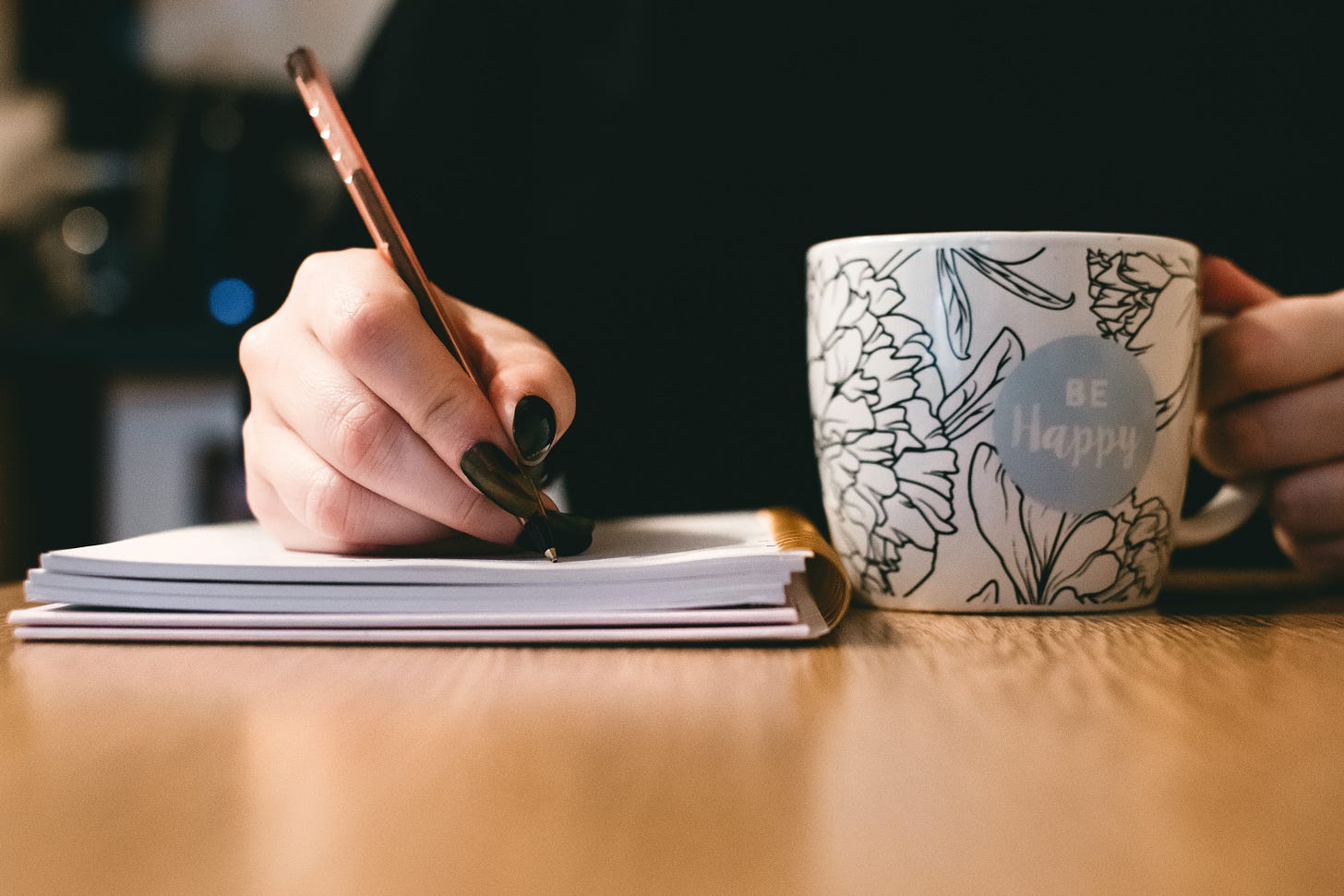 person writing with a mug