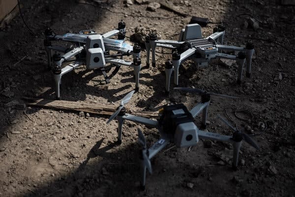 Three small military attack drones sit on a patch of dirt with a splash of sunlight highlighting the middle of the frame. Three small military attack drones sit on a patch of dirt with a splash of sunlight highlighting the middle of the frame.