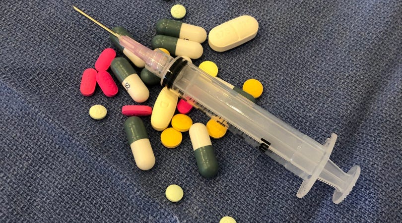 A syringe and colored pills scattered across a table setting a scene for plot twists A syringe and colored pills scattered across a table setting a scene for plot twists